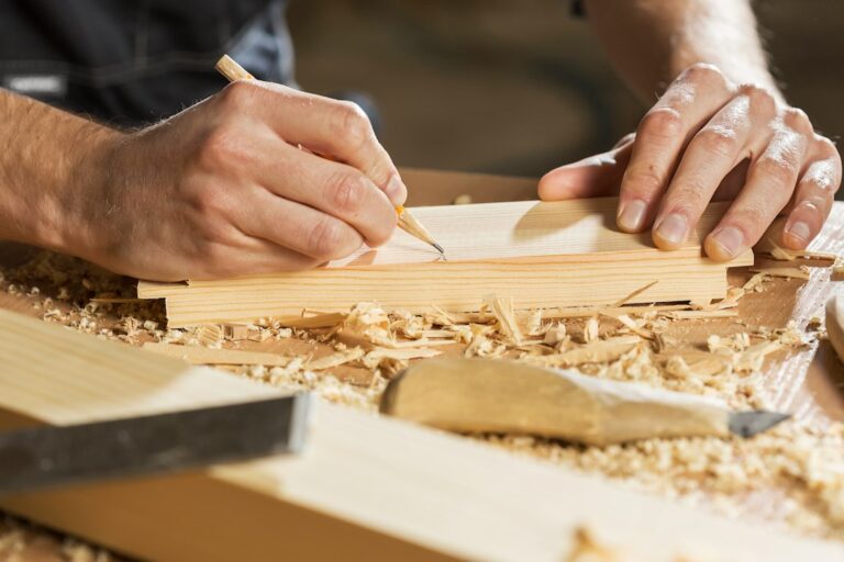 Mantenimiento de Muebles de Madera de Exterior y Tarimas de Terraza: A person marking a line on a wooden board with a pencil