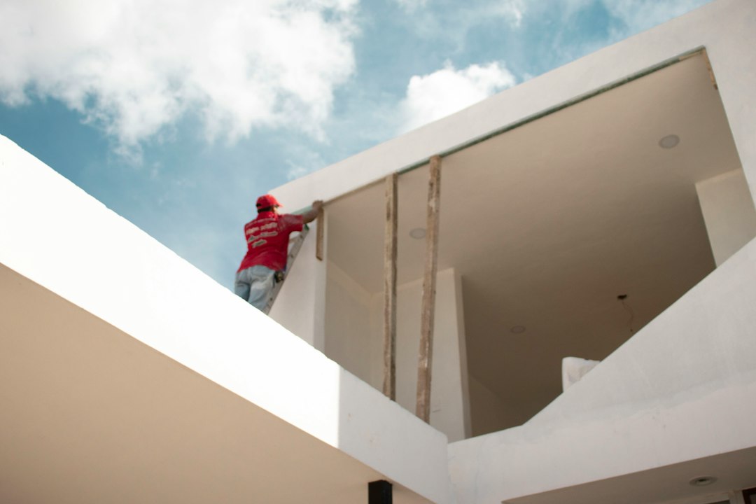 Tratamiento Integral contra el Moho y las Humedades de Condensación en Paredes: man in red jacket standing on white concrete building under blue and white cloud